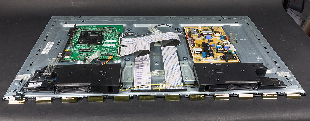 Disassembled flat-screen television with internal boards, speakers and cables exposed